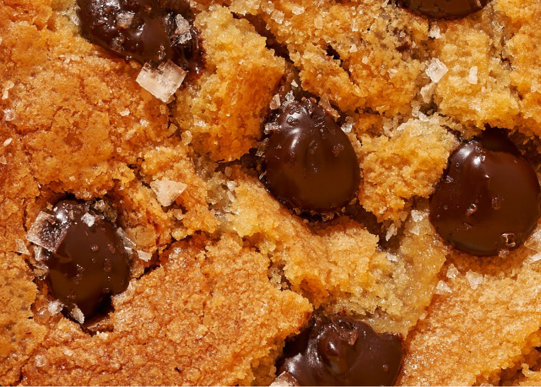 Close-up of a chocolate chip cookie with a yellow background